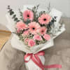 Pink gerbera daisy bouquet wrapped in white paper with a pink ribbon