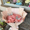 Bouquet of pink roses wrapped in patterned paper with a pink ribbon