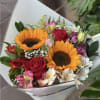 Bouquet of sunflowers, red roses, and mixed pastel flowers wrapped in white paper