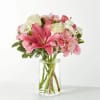 Pink lilies and roses arranged in a clear glass vase
