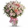 Pink and white rose bouquet in a clear glass vase with a pink ribbon