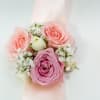 Pink rose wrist corsage with white filler flowers on a pale ribbon