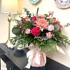 Pink and red mixed flower arrangement in a wrapped vase