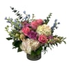 Pink roses and hydrangeas in a glass vase with blue accent flowers