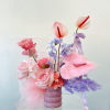 Pink and lavender floral arrangement in a mauve vase with ribbon accents