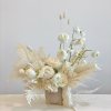 Cream floral arrangement in a beige vase with tall stems and dried accents