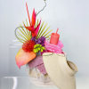 Bright tropical floral arrangement with a woven visor and pink cup