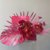 Pink floral arrangement with tropical leaves and a clear vase