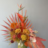 Tropical floral arrangement with orange birds of paradise and yellow roses in a vase