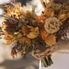 Handheld bouquet of orange and cream flowers with dark foliage