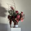 Tall burgundy floral arrangement in a glass vase with branching stems