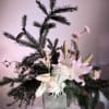 White lilies and roses arranged with pine branches in a square vase