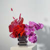 Red roses and purple orchids arranged in a silver vase