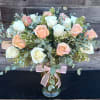 Bouquet of white and peach roses in a glass vase with a pink ribbon