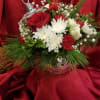 Red and white floral arrangement in a clear ornament-shaped vase