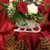 Red and white floral arrangement in a white sleigh container