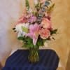 Pink lily and mixed pastel flowers in a glass vase