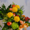 Basket arrangement with yellow mums, orange roses, and green hydrangea
