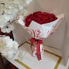 Bouquet of red roses wrapped in white paper with a red ribbon