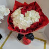 Red roses and white hydrangeas wrapped in red paper with a black ribbon
