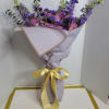Purple and pink bouquet wrapped in lavender paper with a yellow ribbon