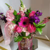 Pink and purple mixed bouquet in a pink glass vase with a ribbon