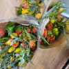 Three wrapped bouquets of orange and yellow tulips with greenery