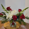Red roses and white lilies in a small vase with evergreen accents