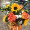 Sunflowers and orange roses arranged in a pumpkin-shaped vase