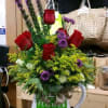 Bouquet of red roses and purple flowers in a white flower pot