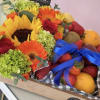 Bouquet with sunflowers, gerbera daisies, roses, and fruit in a box