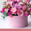 Pink roses and orchids arranged in a round pink box