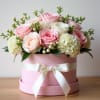 Pink and white roses arranged in a pink hat box with a ribbon