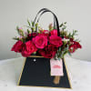 Pink and red roses in a black gift bag with handles