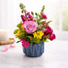 Pink and yellow flower arrangement in a blue ceramic pot