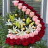 Heart-shaped floral arrangement with red and pink roses and white lilies in a basket
