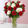 Red roses and white calla lilies arranged in a clear glass vase.