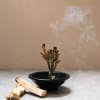 Burning incense sticks in a black bowl with smoke rising