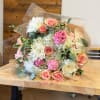 Bouquet of pink and white roses with white chrysanthemums wrapped in clear paper