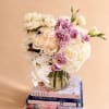 White bouquet with roses, hydrangeas, and orchids in a glass vase