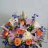 Bouquet of pink lilies, orange roses, and blue flowers in a pink hatbox