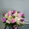Pink roses and purple tulips arranged in a glass vase
