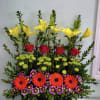 Tall mixed flower arrangement with yellow lilies, red roses, and bright daisies
