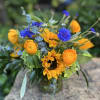 Bouquet of yellow sunflowers and blue flowers in a glass vase