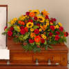 Bright mixed flower spray on a wooden casket