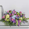 Large floral casket spray with pink roses and purple blooms