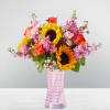 Bouquet of sunflowers, roses, and pink flowers in a striped glass vase