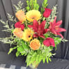 Mixed bouquet of roses, gerbera daisies, and lilies in a glass vase