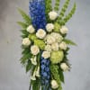 Standing floral spray with white roses, blue delphinium, and green hydrangea