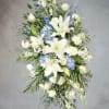 Tall white floral spray with lilies, roses, and blue accents